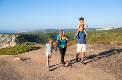 happy family couple children hiking countryside walking path excited boy riding dads neck full length nature recreation concept - Magainepanda.com