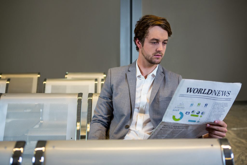MagazinePanda.com Guide to Building a Strong Online Business 4 - Magainepanda.com businessman sitting waiting area reading newspaper - Magainepanda.com